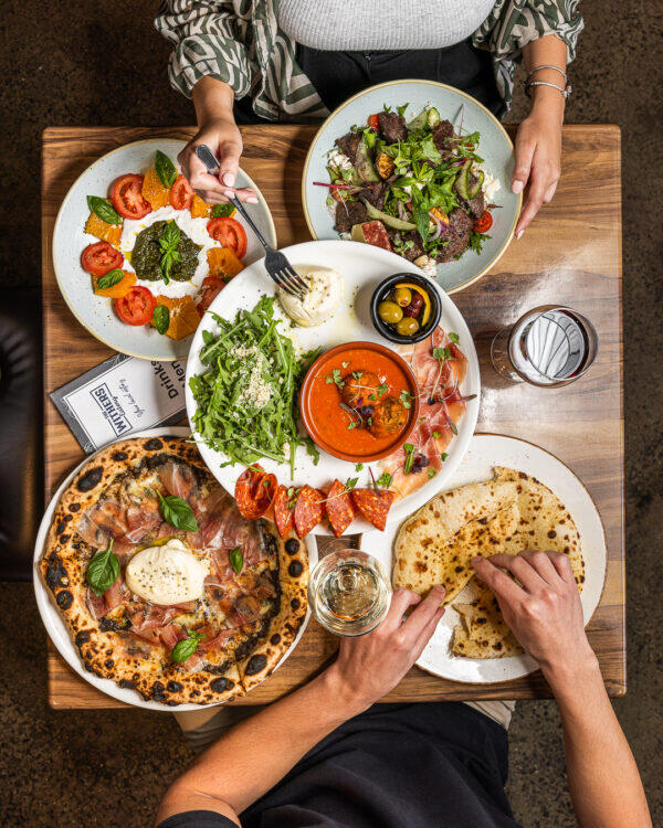 sharing meal table with pizza salad, fresh baked pizzas, Woodfire pizza